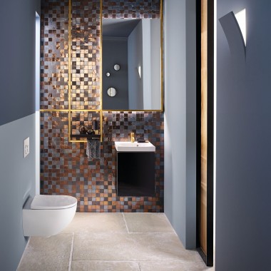 Un moderno bagno per gli ospiti con WC e lavabo Acanto con rivestimento parete a mosaico