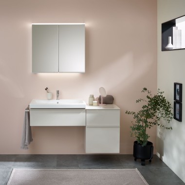 Zona lavabo con mobili da bagno, lavabo e mobile specchio di Geberit davanti a una parete color pastello
