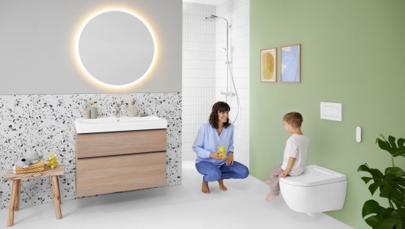 Donna e bambino in un bagno dai colori vivaci con specchio Geberit Option e Geberit AquaClean Alba