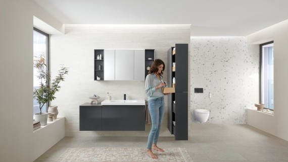 Donna che apre un mobile alto con tanto spazio contenitivo in un bagno con mobili Geberit Acanto Donna che apre un mobile alto con tanto spazio contenitivo in un bagno con mobili Geberit Acanto